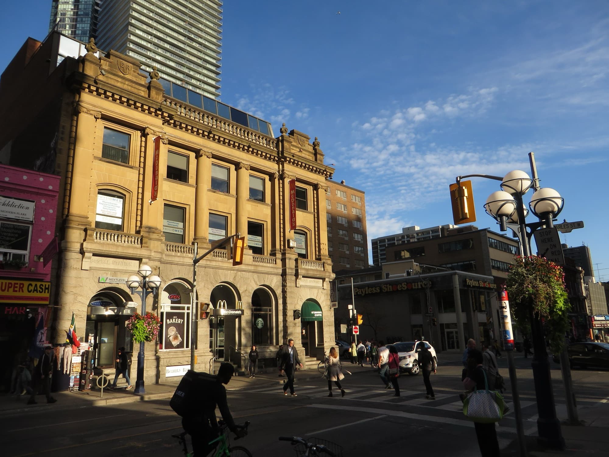The corner of Yonge Street and Charles Street in Toronto, with a stone bank building and towers behind