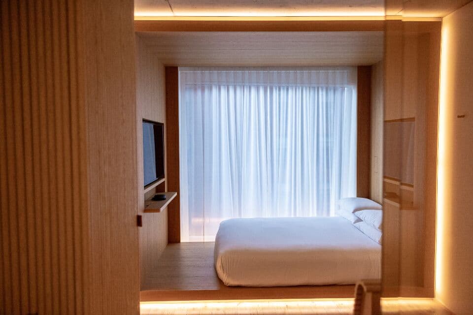 Compact room with a bed, screen and full-height curtain