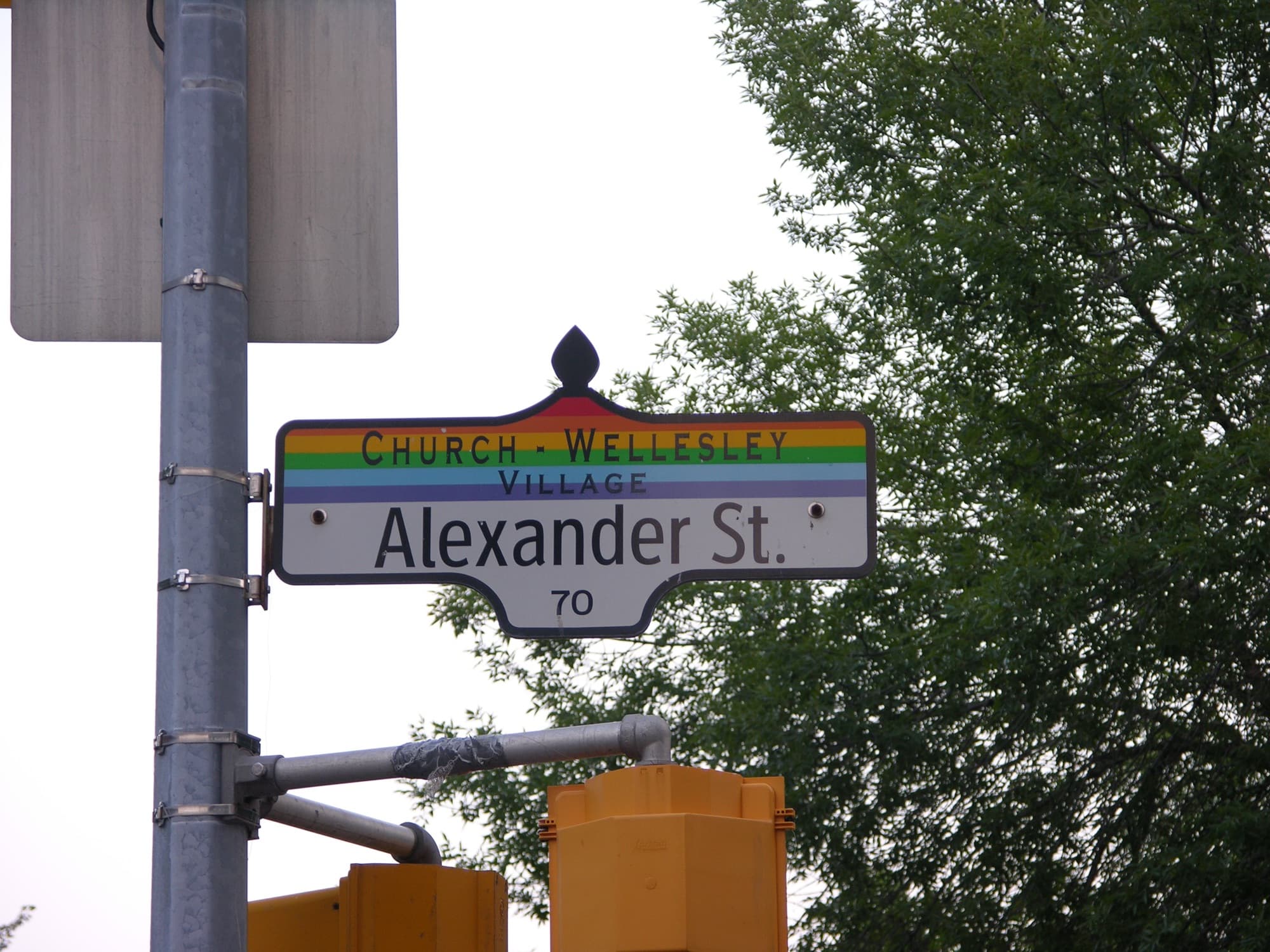 A Church-Wellesley Village street sign with a rainbow band, at Alexander Street