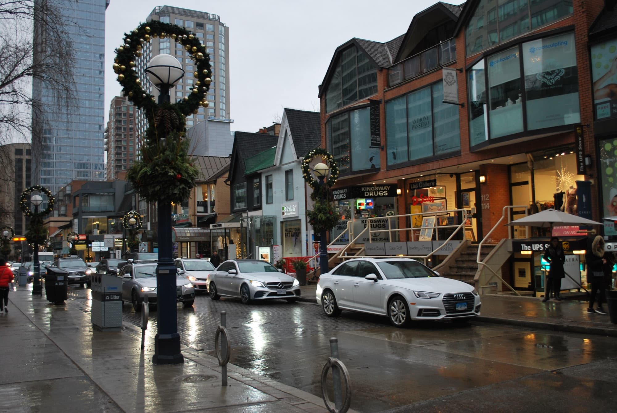 Cumberland Street in Yorkville on a wet evening, with shops and parked cars