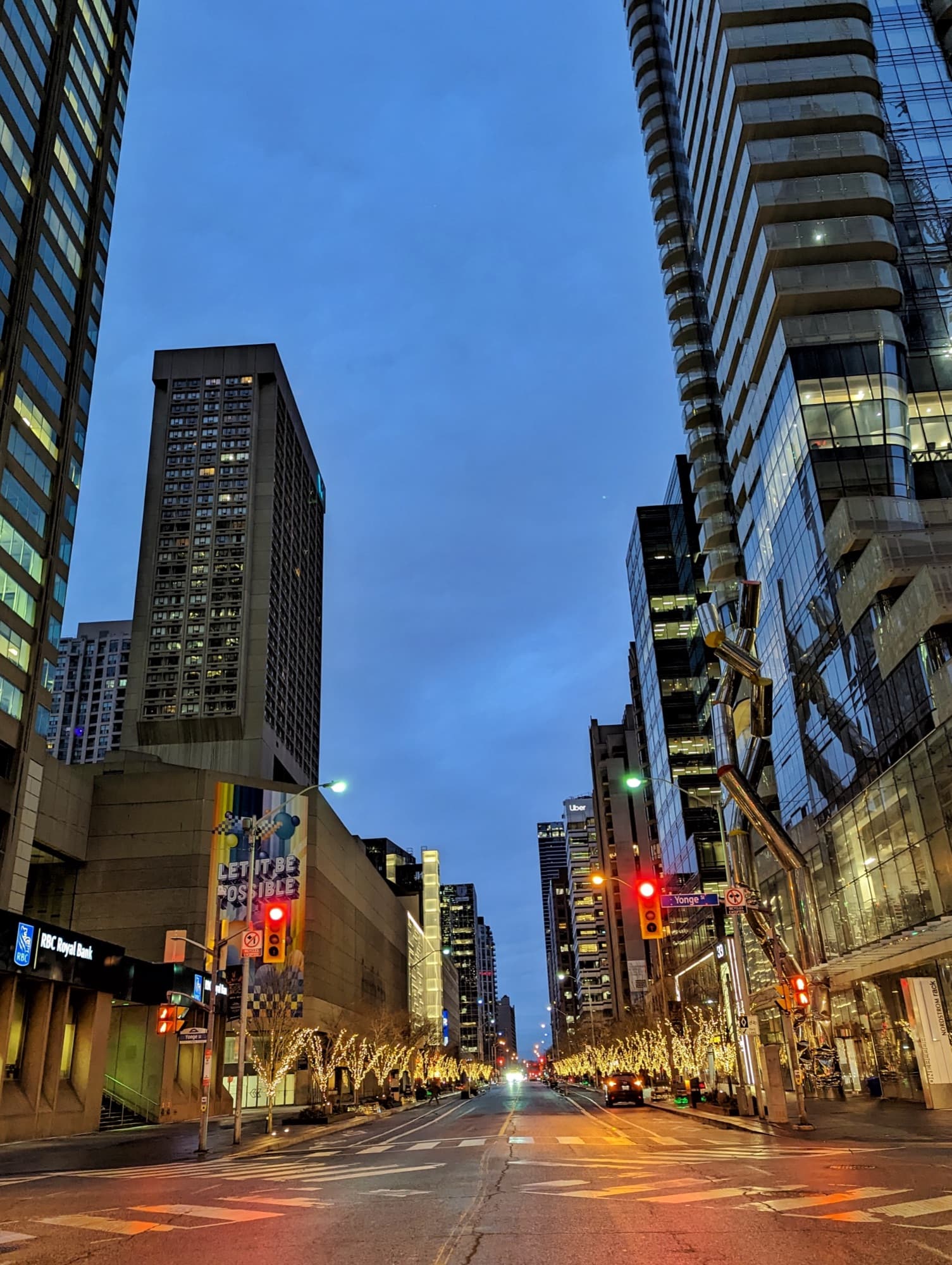 Yonge Street at Bloor at dusk, with towers on both sides and the road lit below