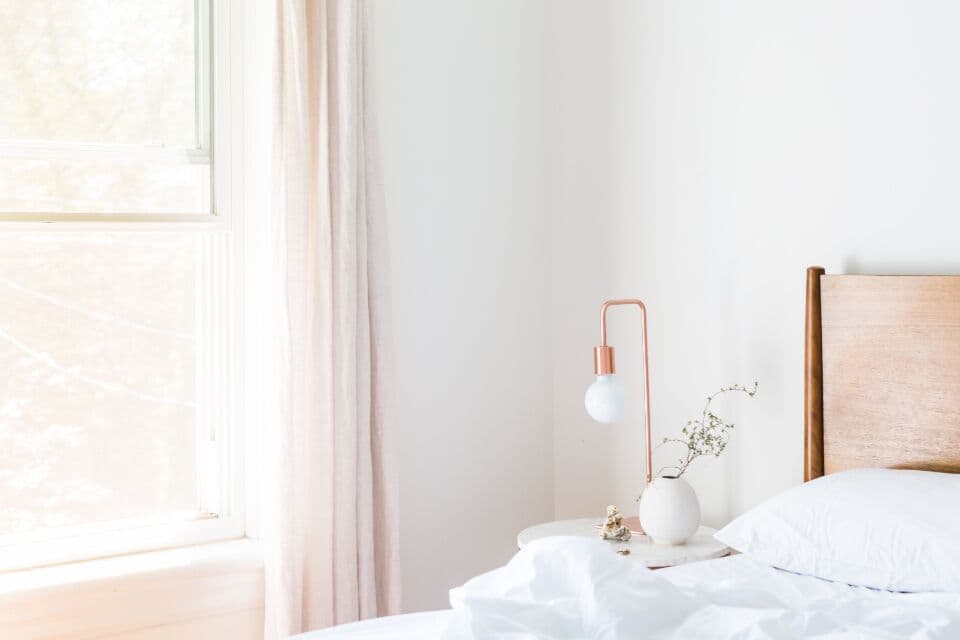 Furnished bedroom with a made bed, bedside lamp and window